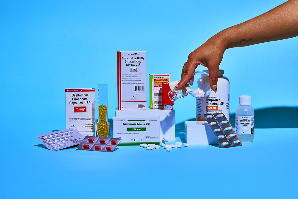 A person dumping prescription pills into a backdrop with various medications.
