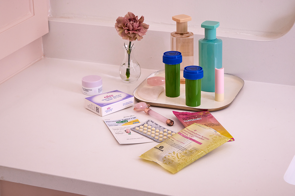A pink counter with a variety of women's health medications on top.