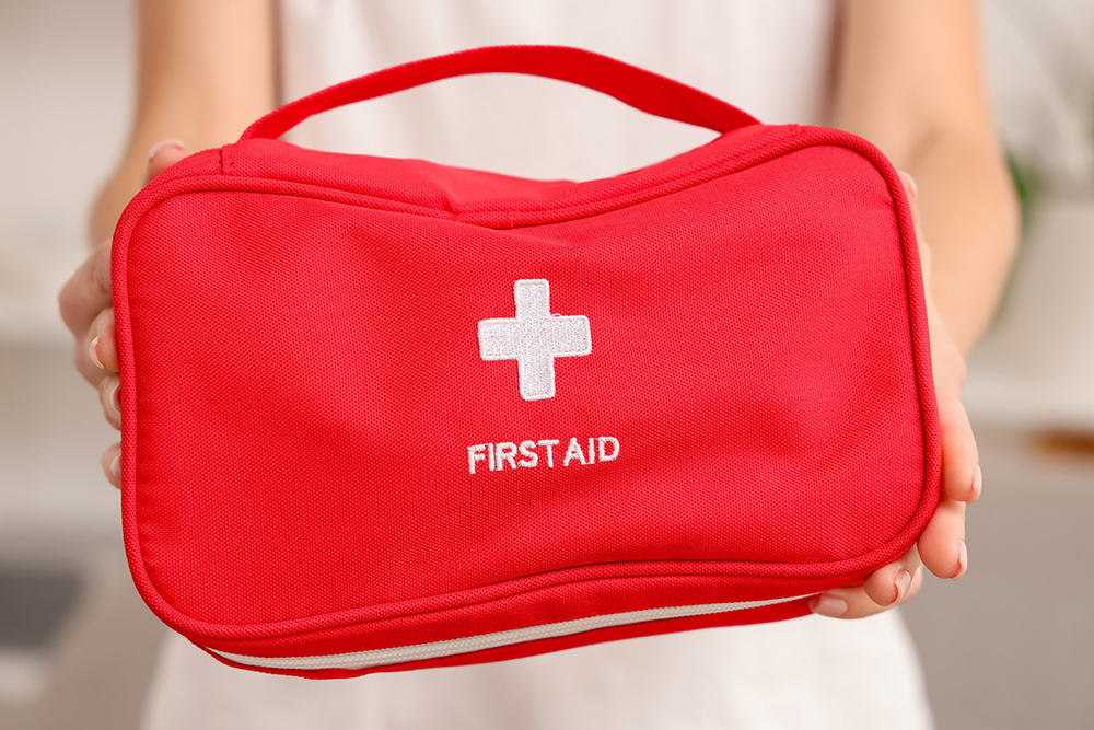 A red First Aid kit being held for a photo.