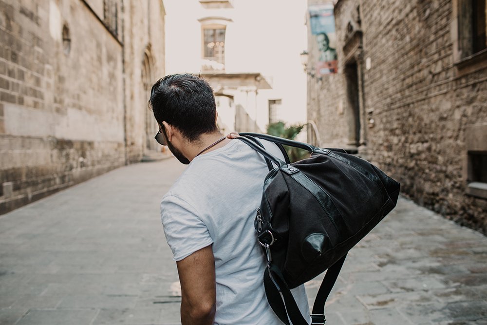 a man strolling down a street with a duffle bag