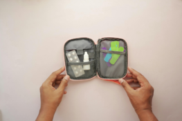 A mini travel first aid kit with bandages, eye drops, and allergy medication.