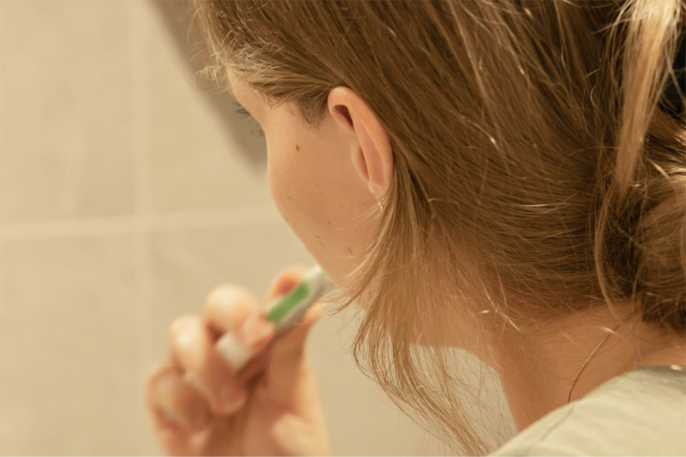 A woman brushes her teeth in the bathroom.