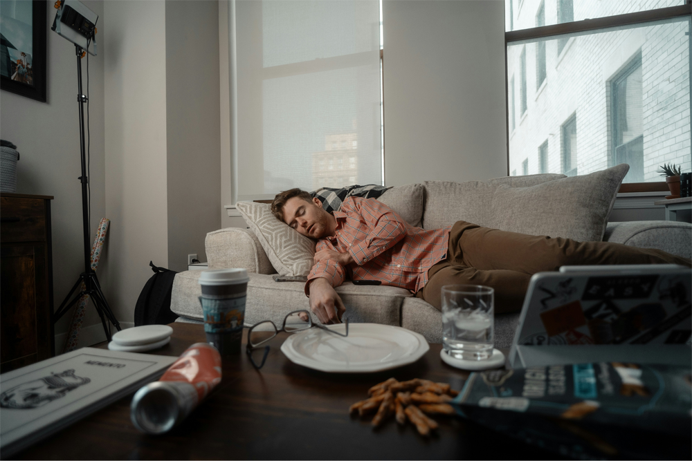 A man rests on the couch after a large meal.