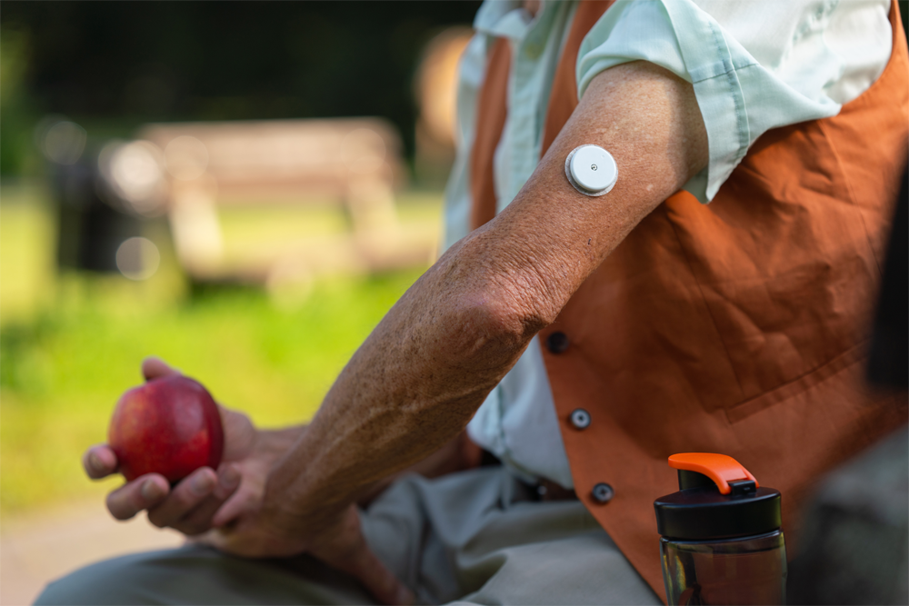 A patient wears a CGM on their arm while working outside.