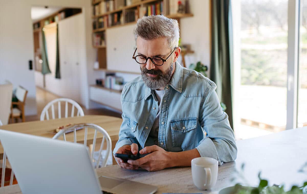 Older man researching online ED treatments on his phone.