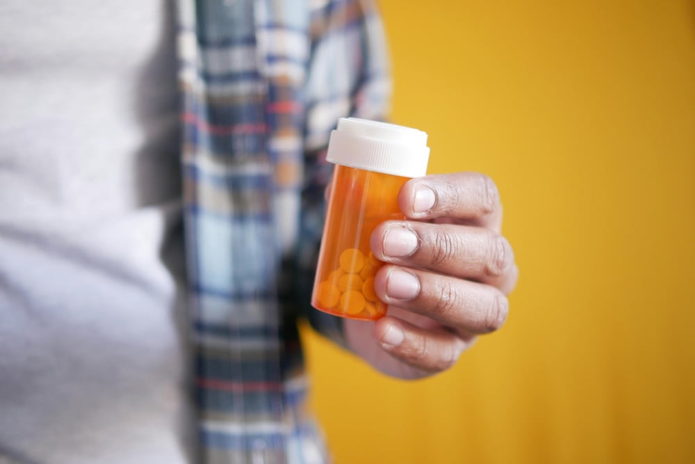 Man holding a bottle of blood pressure medication.