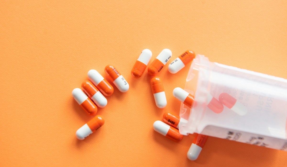 STI treatment medication on an orange background.