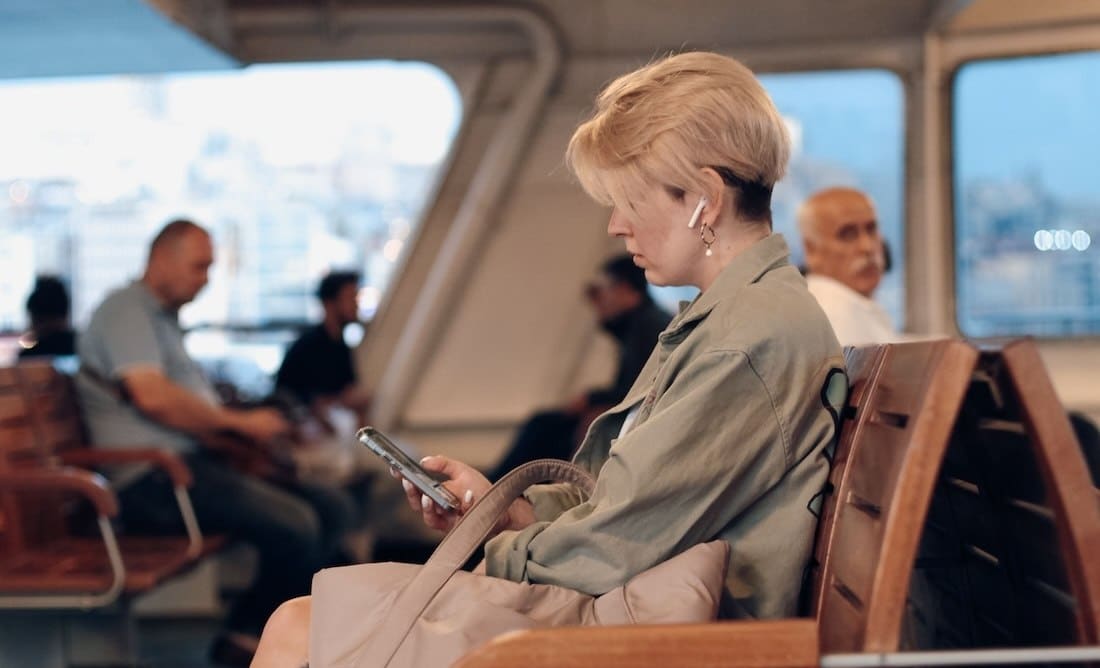 Woman with headphones in looking at her phone during ferry commute