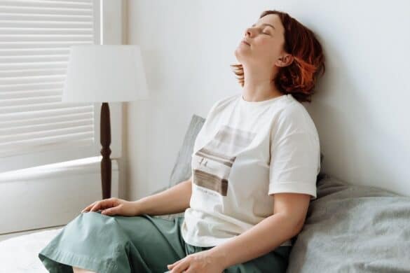 Individual in casual clothing leaning back against the wall looking tired