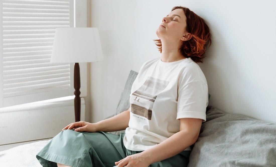 Individual in casual clothing leaning back against the wall looking tired