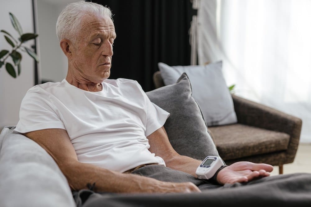 Man checking his blood pressure at home to monitor for common vascular conditions correlated with high cholesterol.