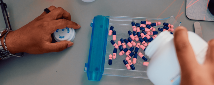 Hands sorting medication into a pill organizer